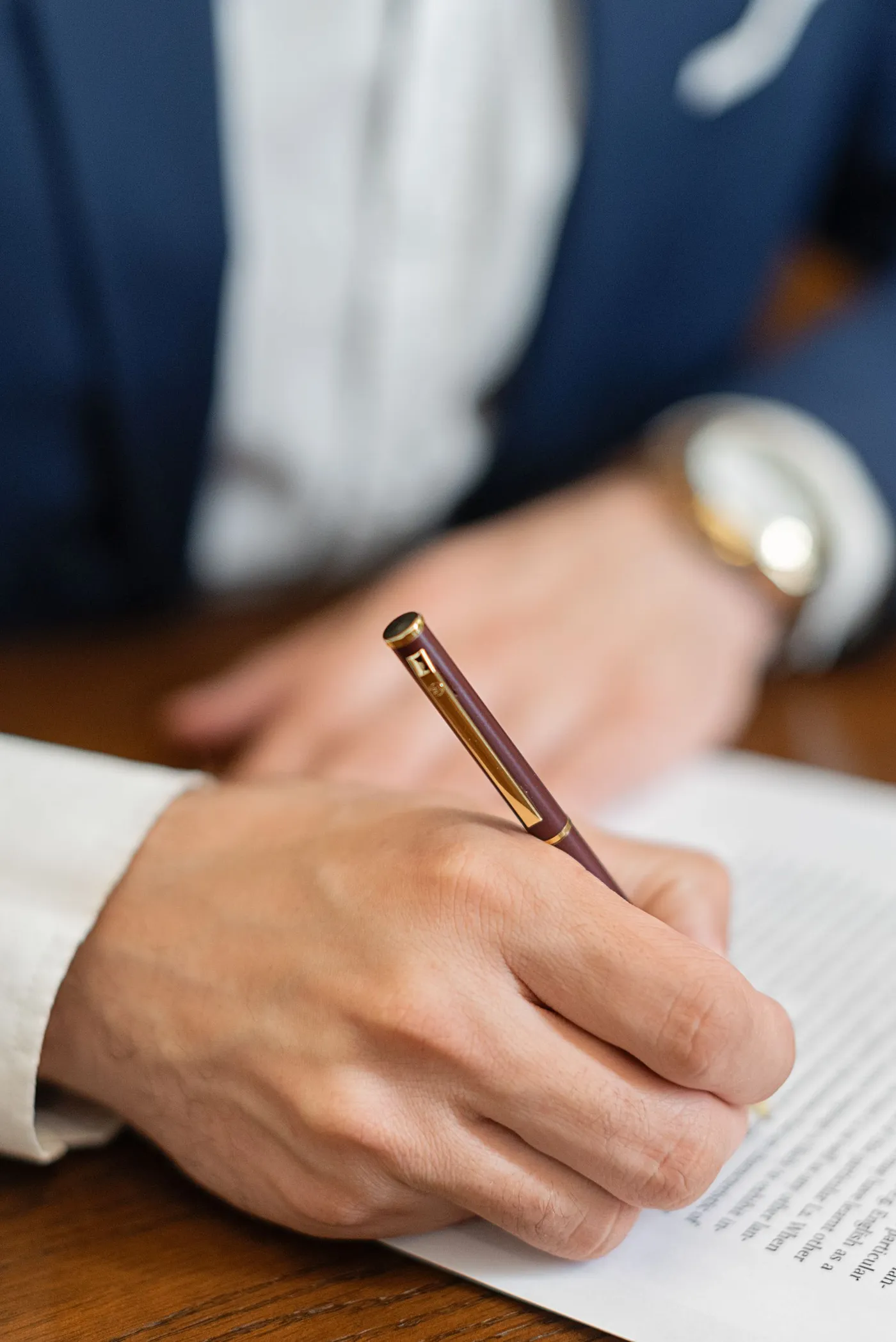 A solicitor signing a document with a burgundy and gold pen
